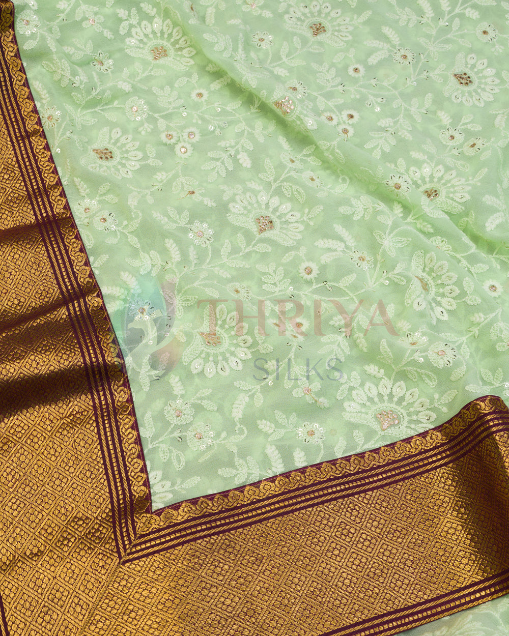 Close-up of light green Chikankari silk saree with intricate floral embroidery and gold border