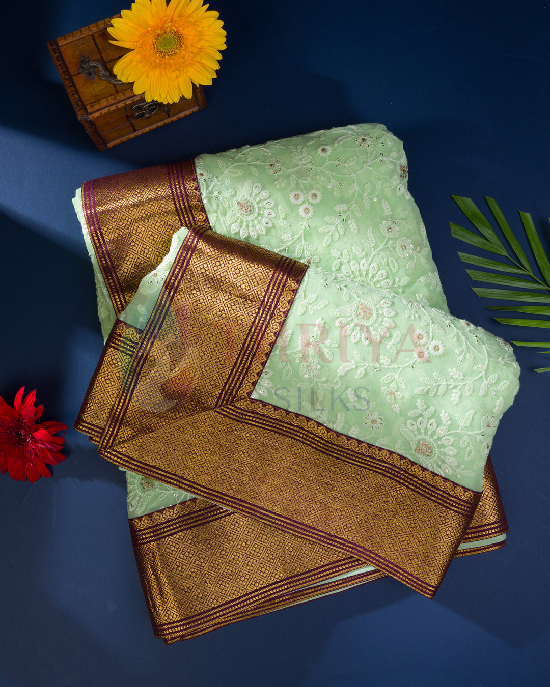 Light green Chikankari Kanchi silk saree with gold zari border, styled on dark blue background with flowers