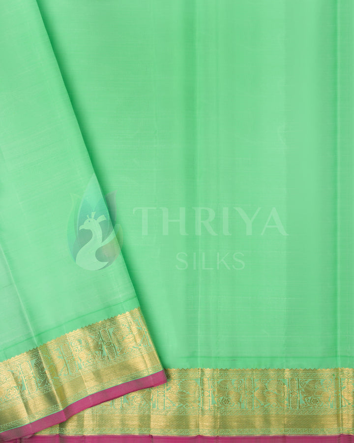 Plain light green blouse piece with gold zari border and pink selvedge matching the saree body