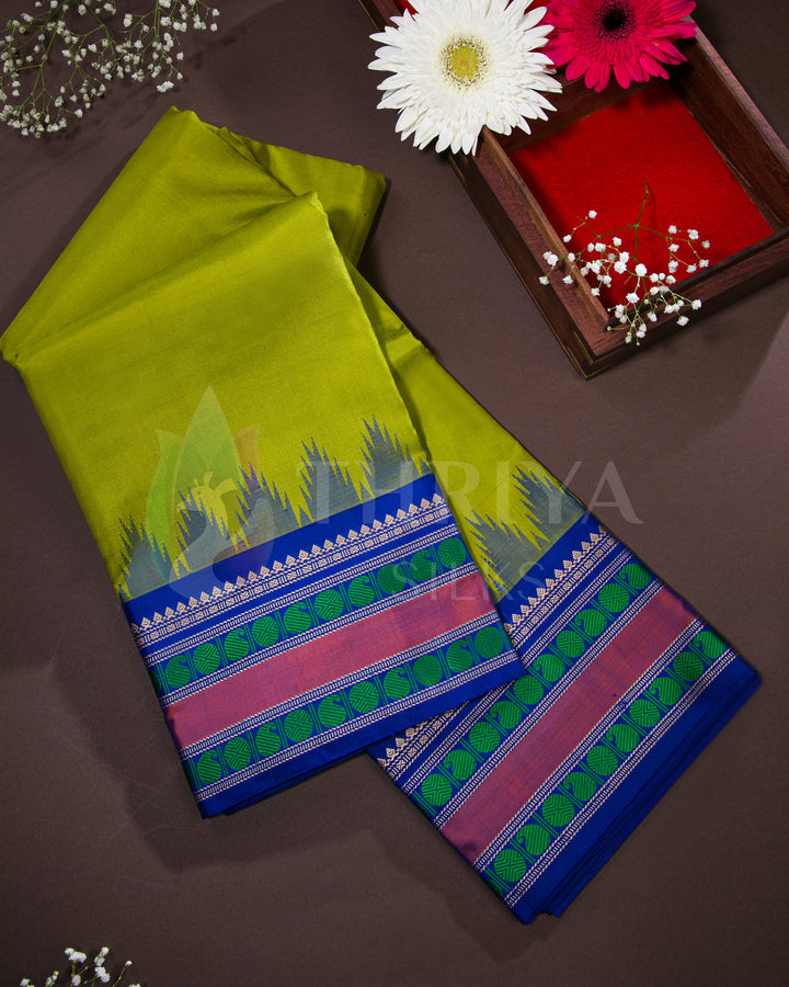 Lime green silk saree with rich blue zari border and floral motifs, neatly box-folded for display.