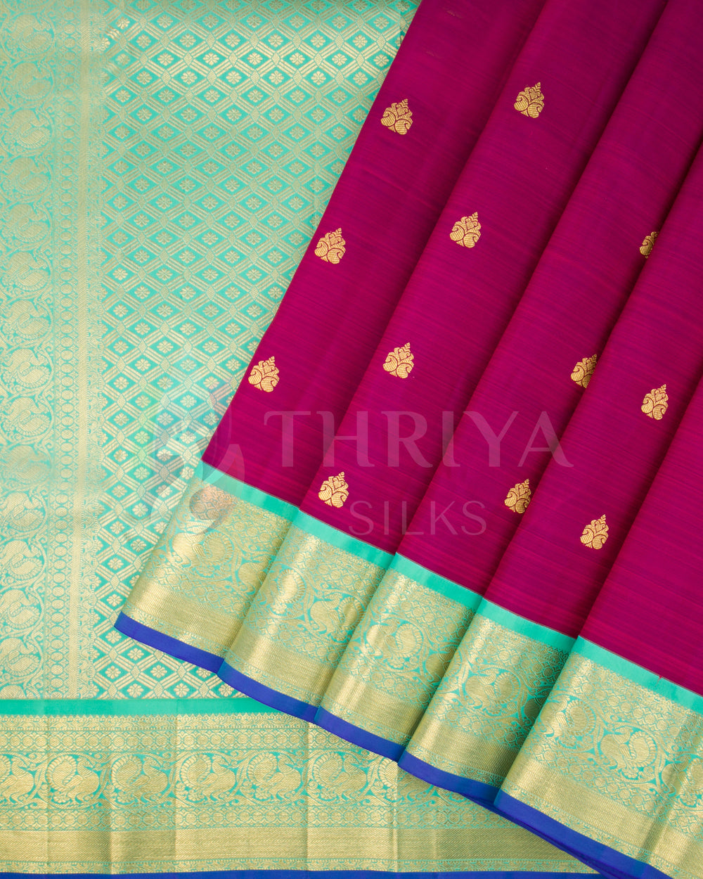 Pleats view of magenta silk saree with golden motifs and sea green zari border