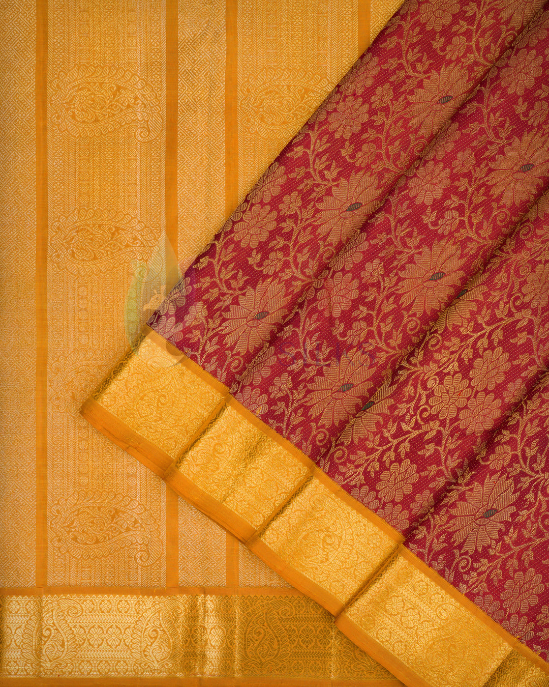 Partial folded flat lay of maroon and gold Kanchipuram silk saree highlighting intricate floral motifs and rich golden zari border
