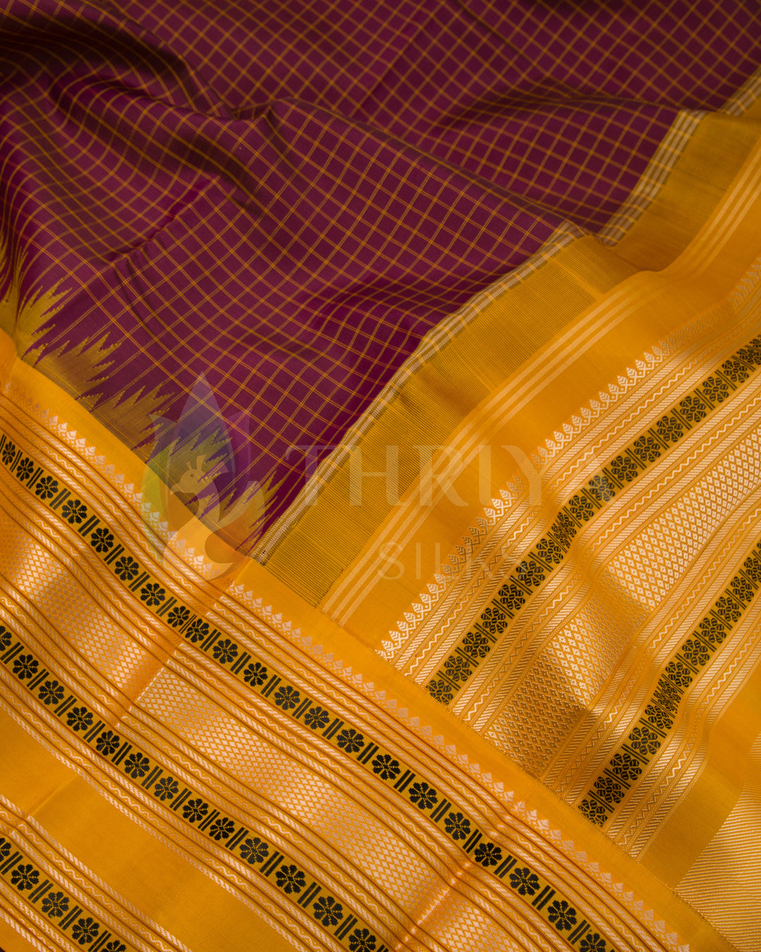 Close-up of maroon Kanchipuram silk saree with mustard yellow pallu and rich zari detailing