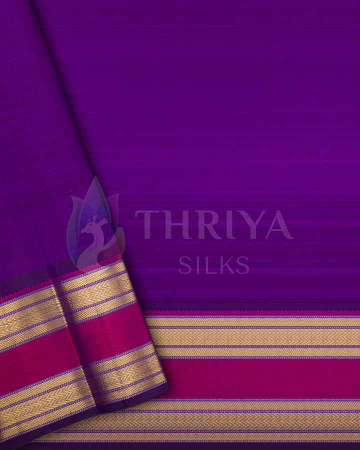 Folded close-up flat lay of Kanchipuram silk saree showing rich purple pallu, gold zari border, and contrast red-gold edging.