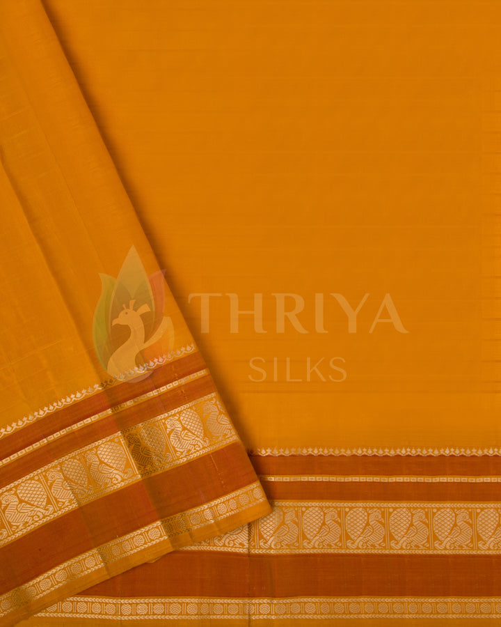 Mustard yellow blouse piece with traditional gold zari border paired with red saree from Thriya Silks