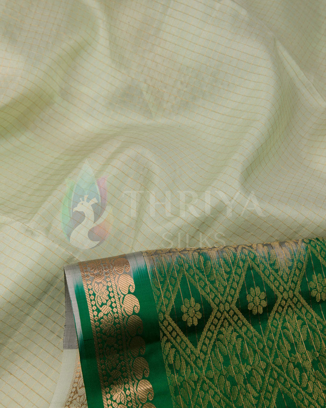 Close-up of soft off-white silk saree with elegant golden zari and green border detail