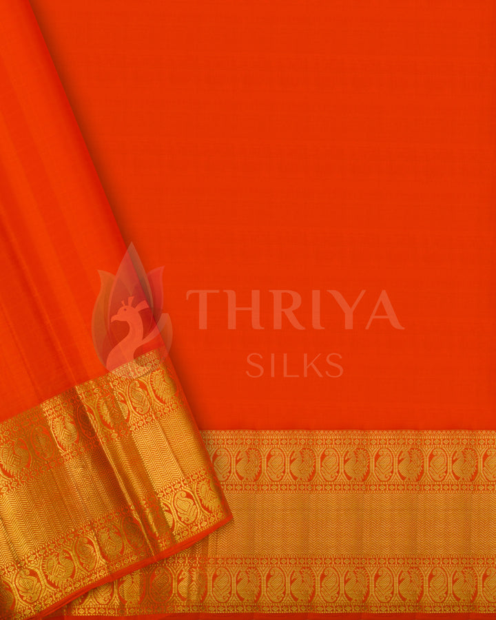Plain orange blouse piece with gold zari border, complementing the pink bird and lotus motif silk saree.