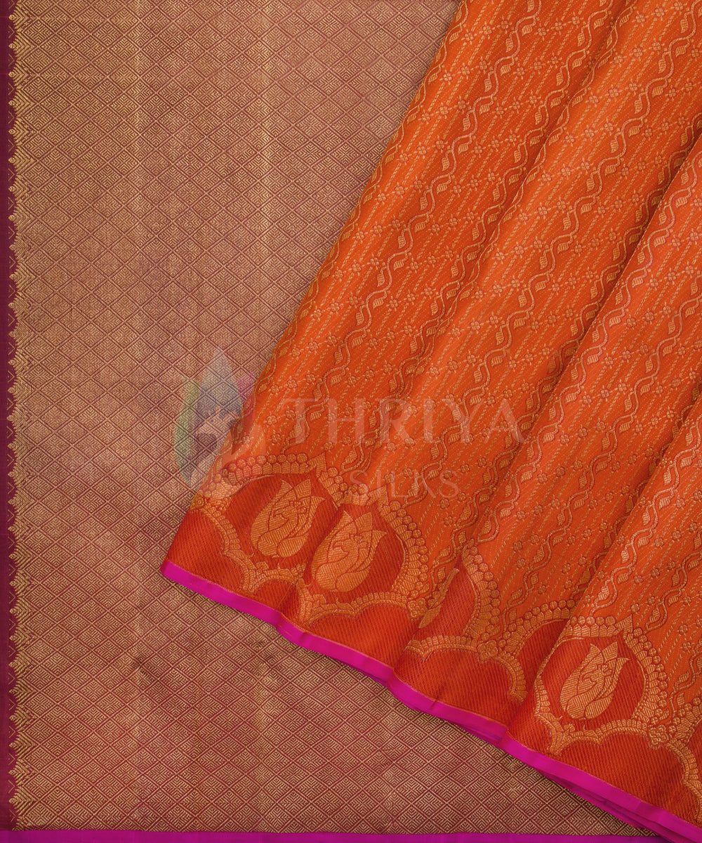 Vibrant orange Kanchipuram saree with bold golden motifs and rich zari detailing along the border.