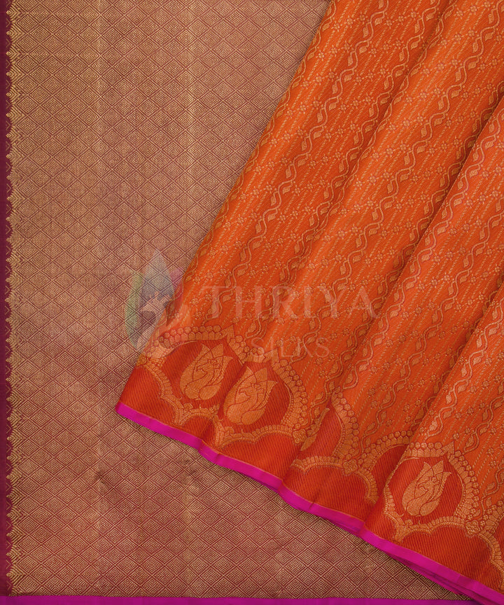 Vibrant orange Kanchipuram saree with bold golden motifs and rich zari detailing along the border.