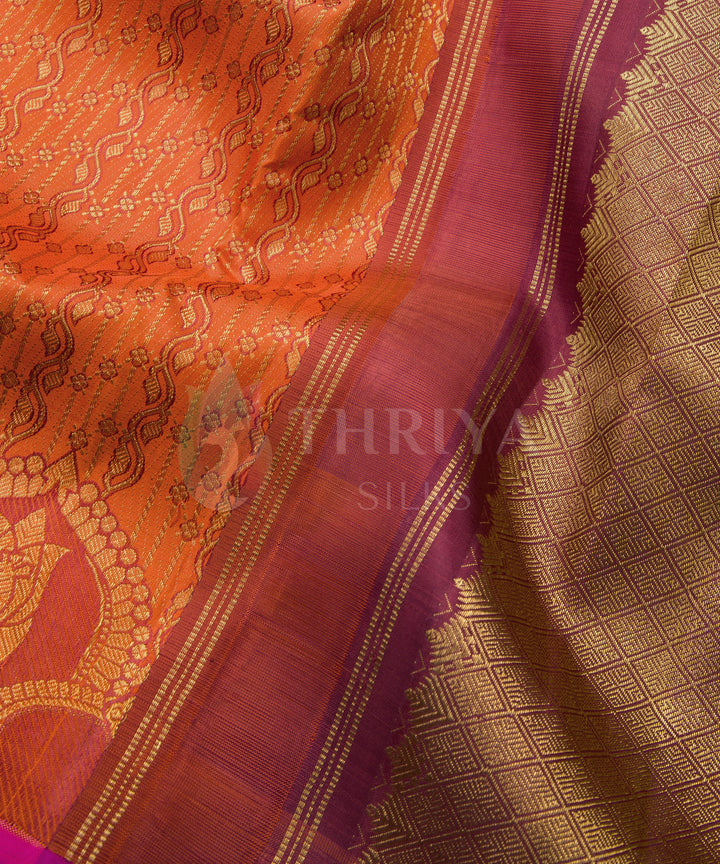 Close-up of a luxurious orange Kanchipuram silk saree with gold zari work and purple border detailing