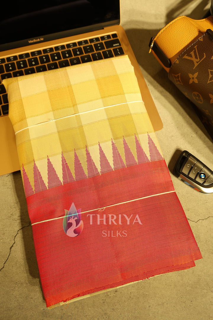 Folded orange and yellow checked silk saree displayed with luxury items.