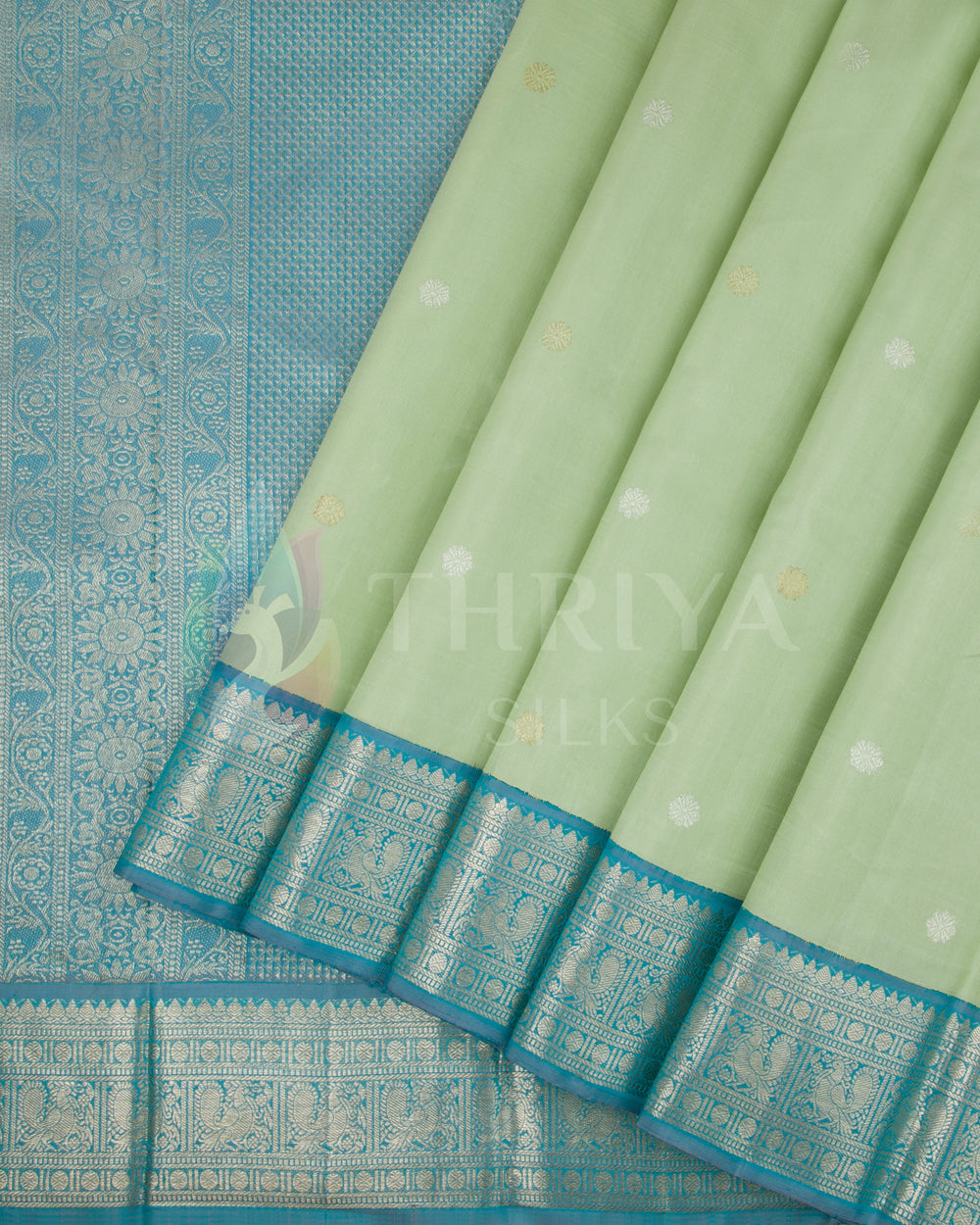 Pleats view of pastel green silk saree with turquoise blue zari border and buttas