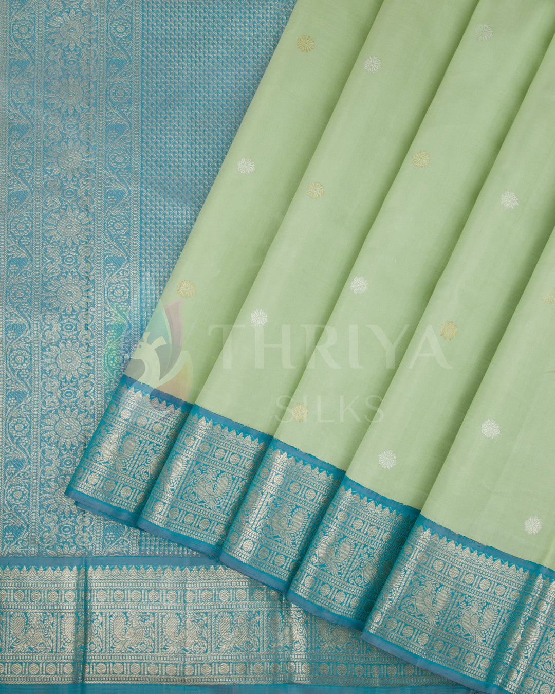 Pleats view of pastel green silk saree with turquoise blue zari border and buttas