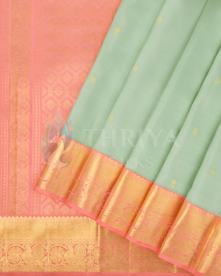 Pleats view of pastel green silk saree with gold motifs and peach-pink border in gold zari weaving
