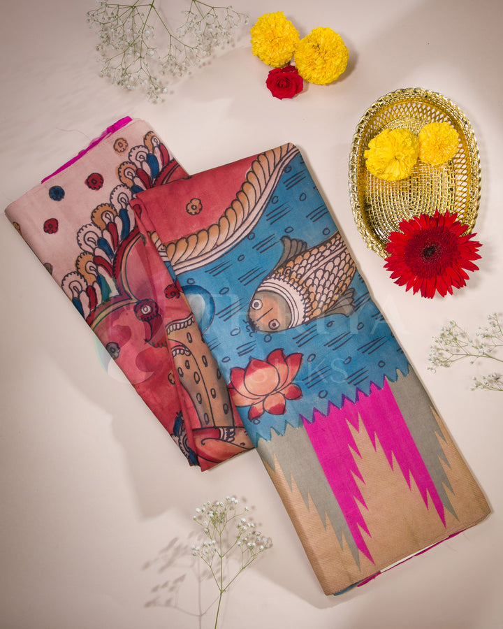 Folded view of pink and blue Kalamkari silk saree with fish and deity motifs, paired with golden zari detailing.