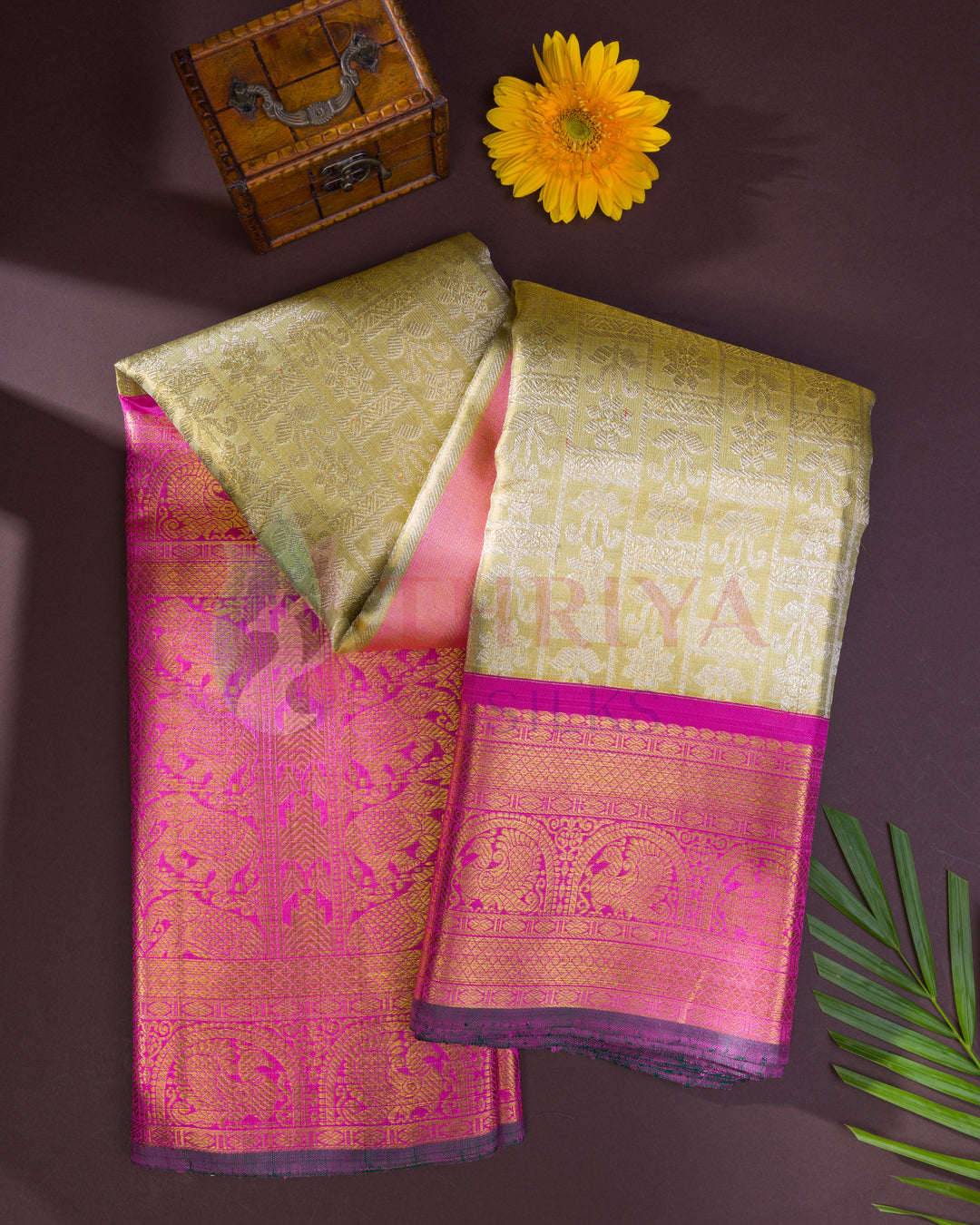 Detailed close-up of pink and gold Kanchipuram silk saree textile, focusing on intricate floral and traditional patterns