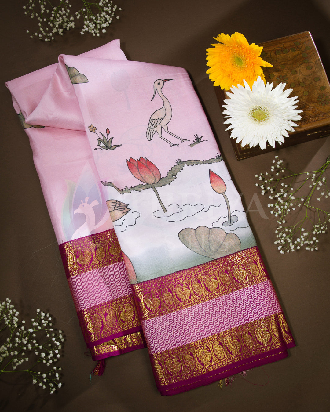 Folded view of light pink silk saree with swan, lotus, and nature motifs paired with magenta and gold zari border.