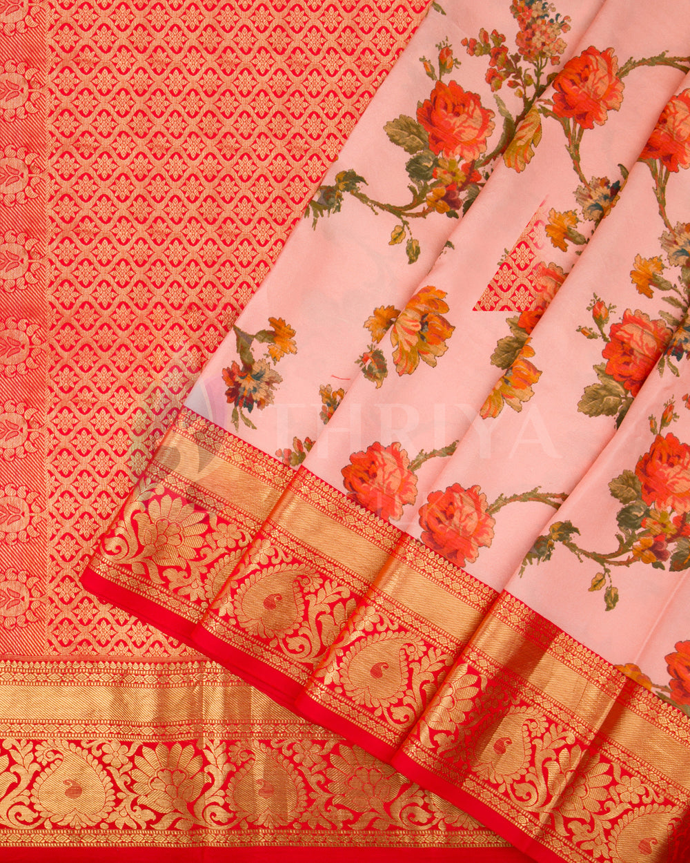 Pleated view of the floral Banarasi saree with blush pink base, red border, and intricate golden zari motifs.