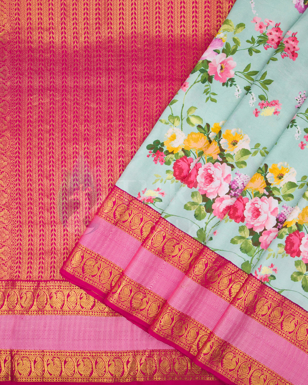 Pleated view of mint floral silk saree with contrast pink zari pallu and border details.