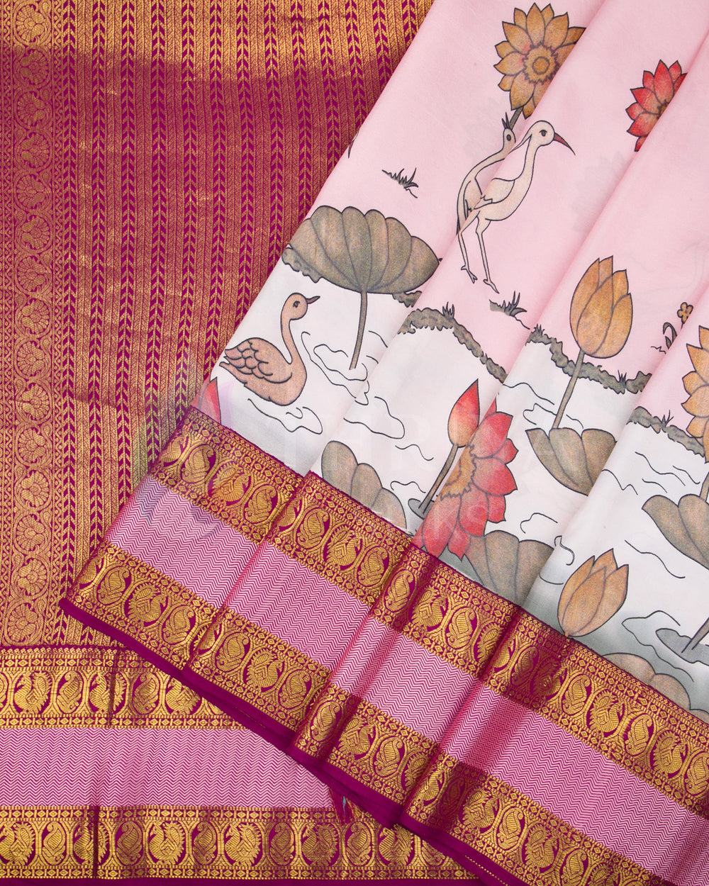 Pleated view showcasing swan and lotus designs on the pink base with rich magenta zari pallu and border.