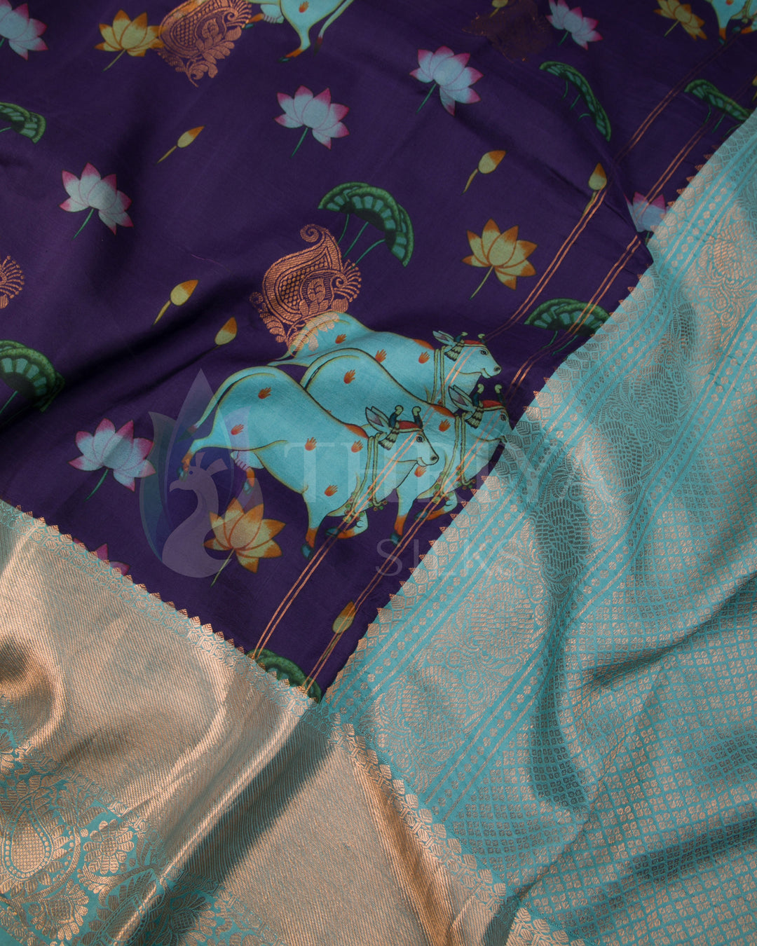 Close-up view of blue elephant motif and silver zari border on rich purple silk base