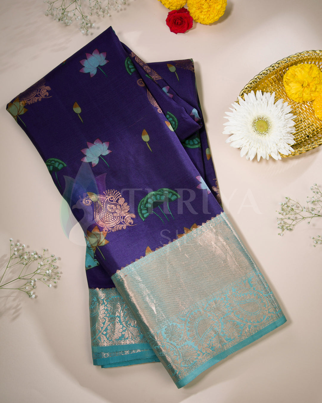Folded view of purple silk saree with floral and elephant motifs paired with aqua silver zari border.