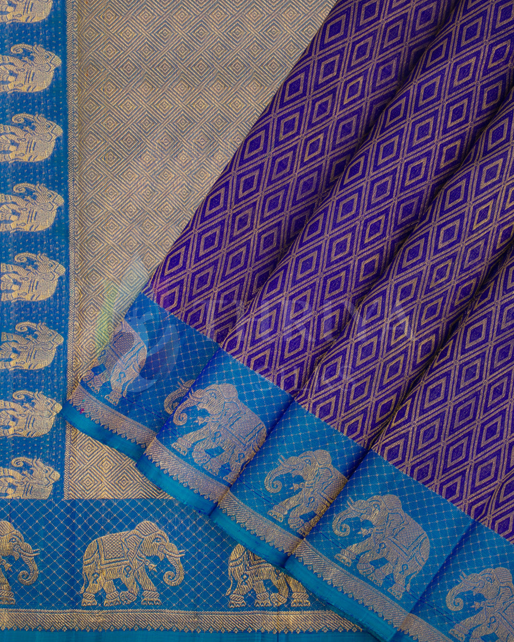 Pleated view of royal purple Kanjivaram silk saree with peacock blue border and gold elephant motifs