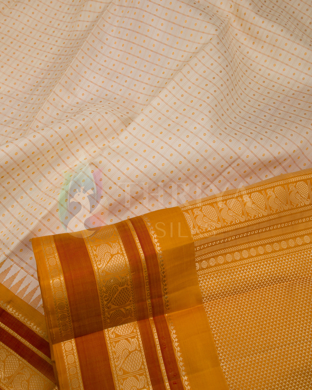 Close-up of cream silk saree with intricate gold zari and dual-tone orange border