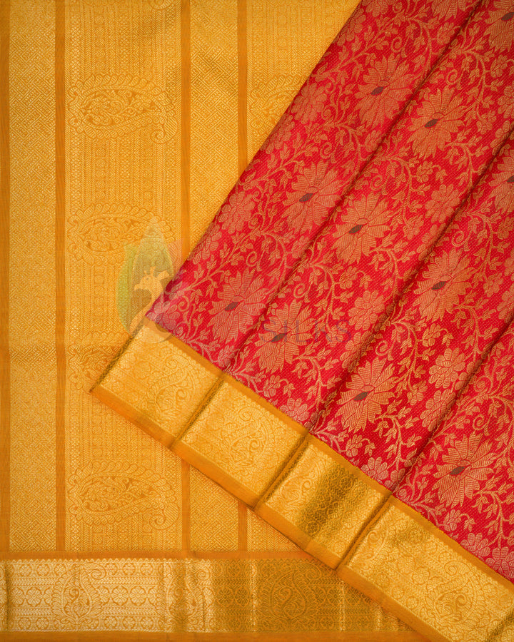 Partial folded flat lay of red and gold Kanchipuram silk saree showcasing floral motifs and rich golden zari border