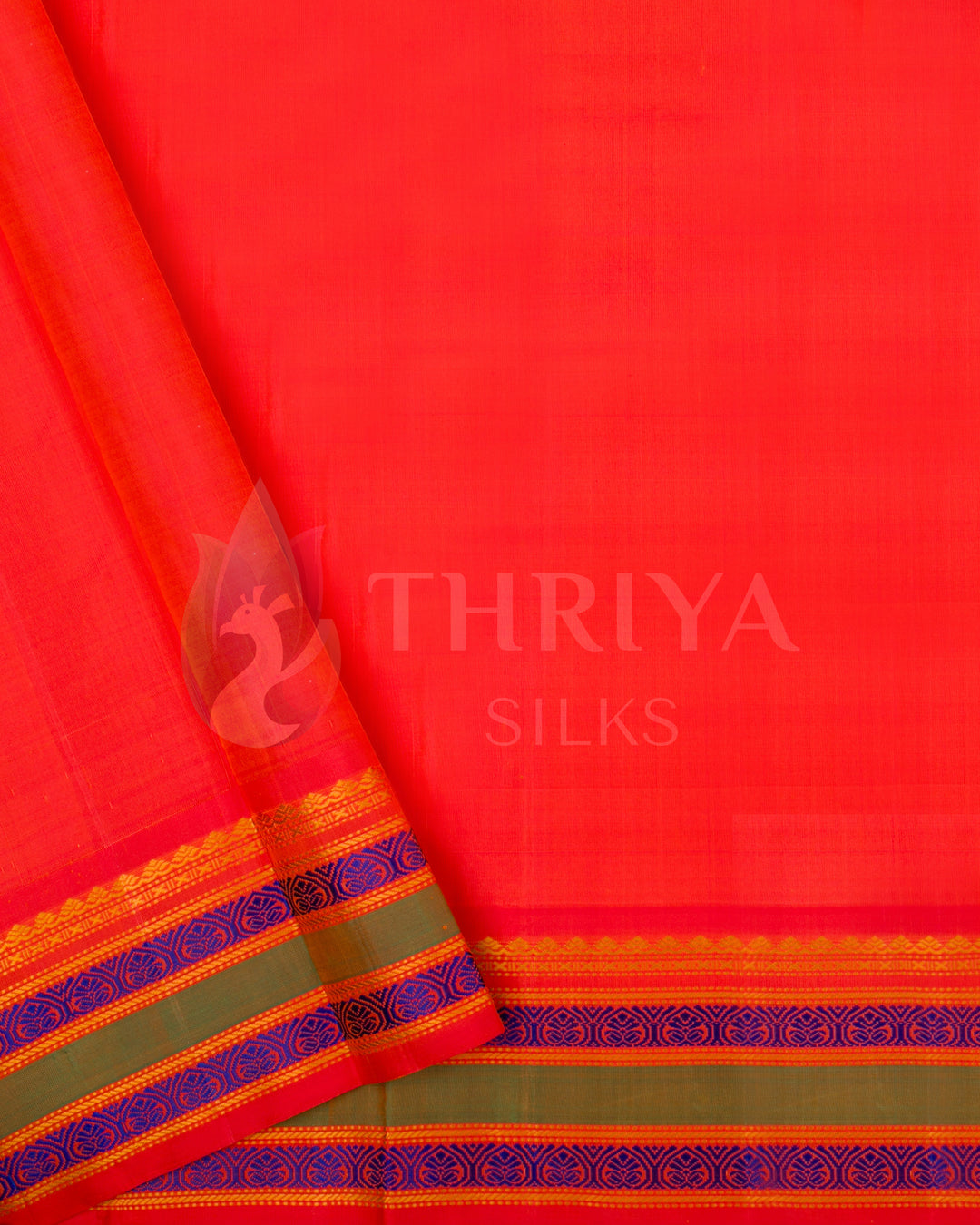 Plain red-orange blouse piece with blue and green zari border, paired with beige saree from Thriya Silks
