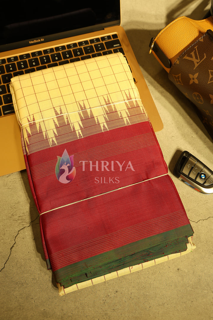 Folded red and cream silk saree showcased with a car key and laptop for luxury styling.