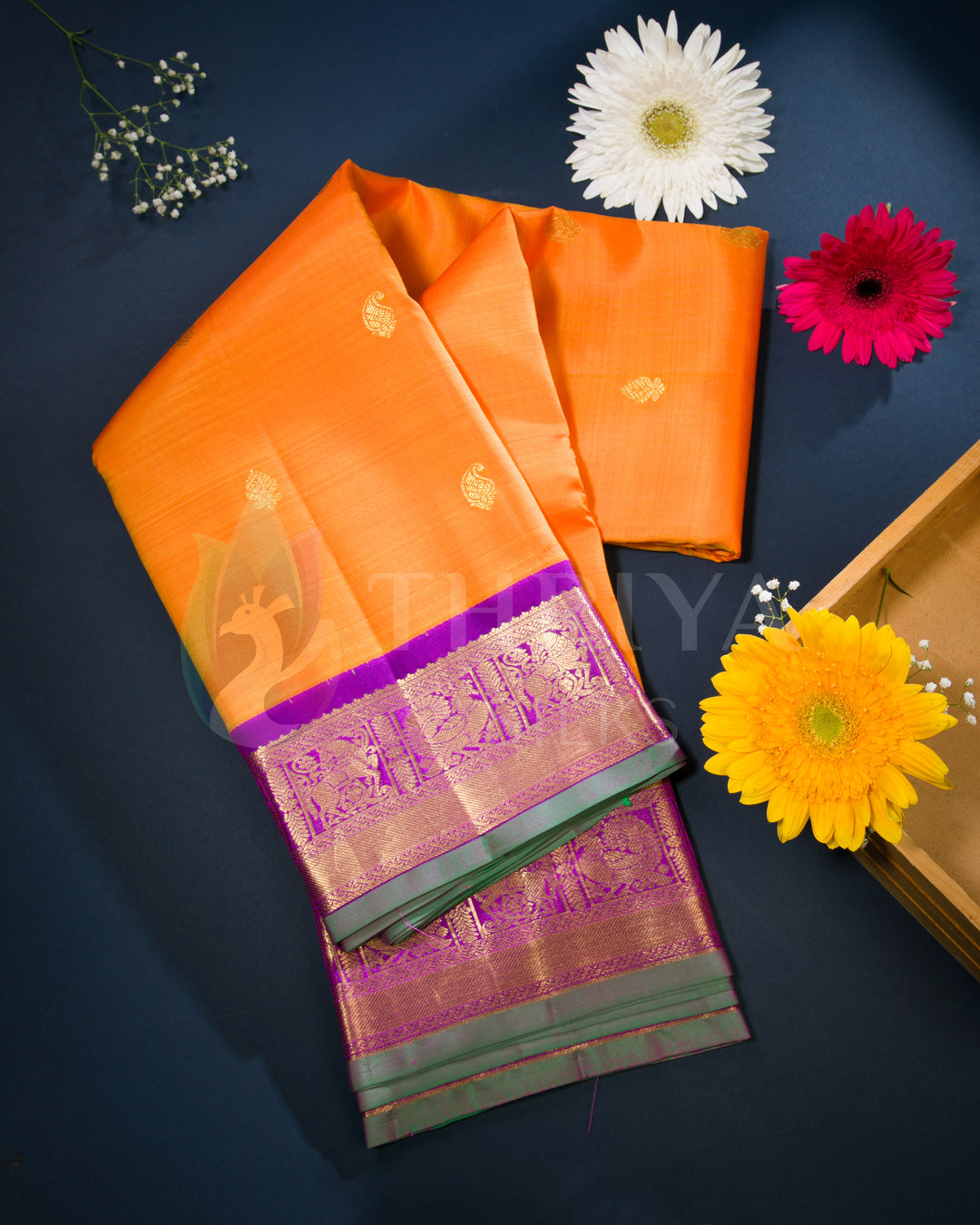 Styled view of orange silk saree with purple zari border and golden floral buttas