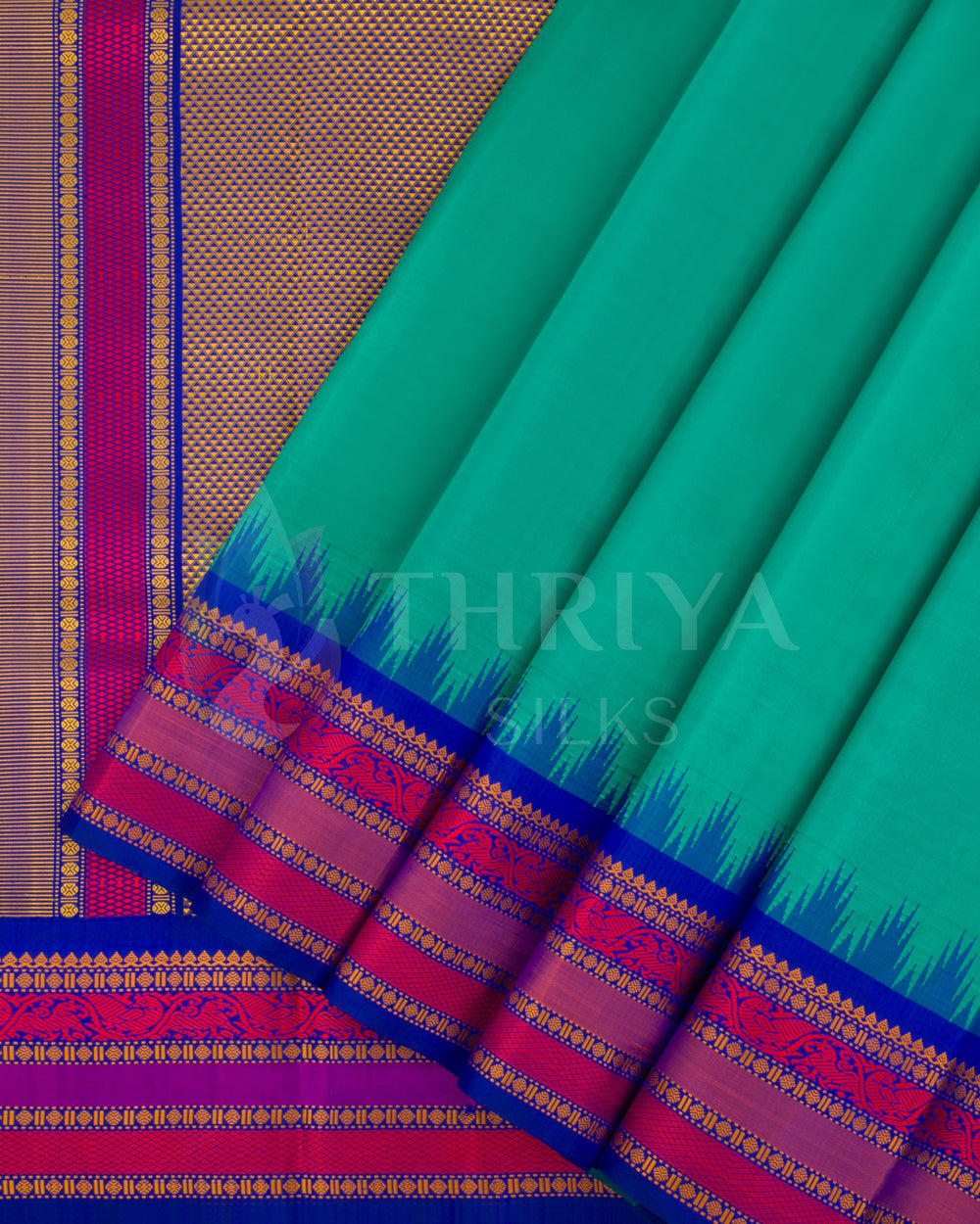 Teal green silk saree with royal blue and magenta zari border – front pleated view from Thriya Silks