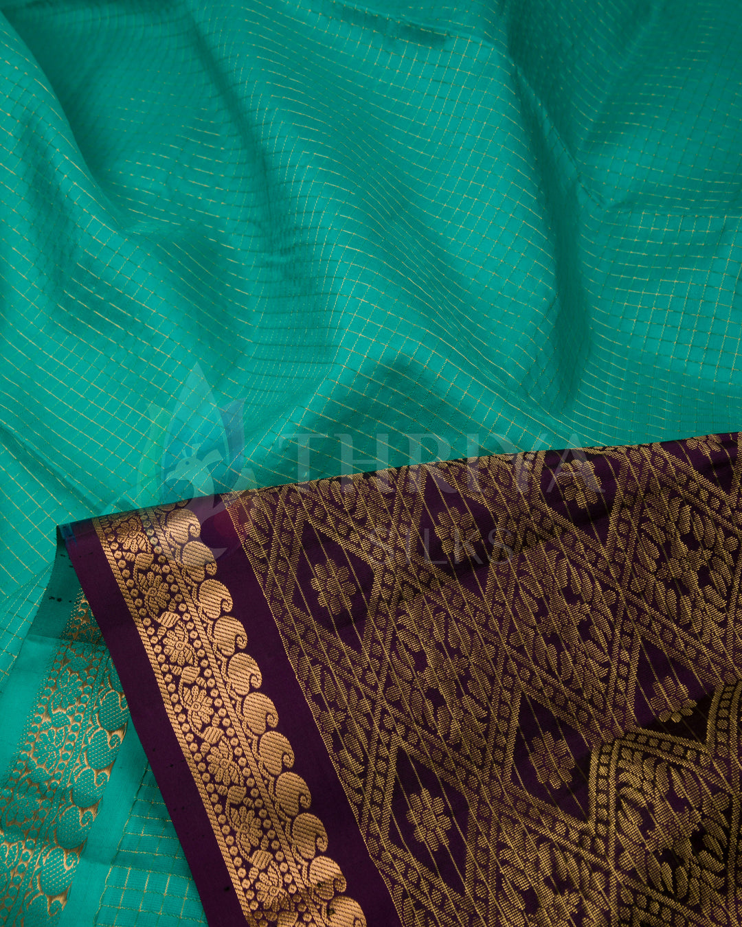 Close-up showing the green silk body with gold zari lines and ornate purple pallu border.
