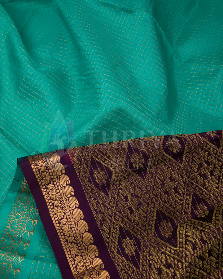 Close-up showing the green silk body with gold zari lines and ornate purple pallu border.