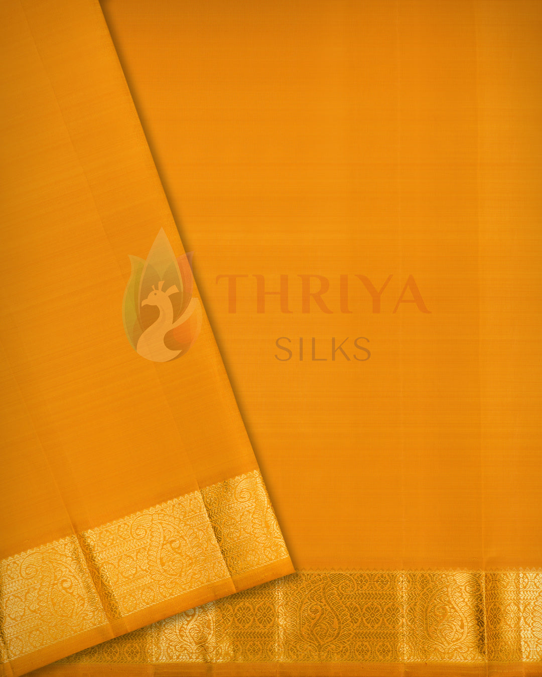Close-up angled view of folded mustard yellow Kanchipuram silk saree showcasing smooth fabric texture and golden zari border
