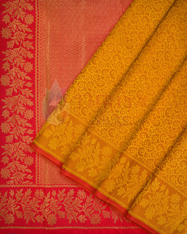 Yellow-orange Kanjivaram silk saree with intricate floral golden zari weave and contrasting red border