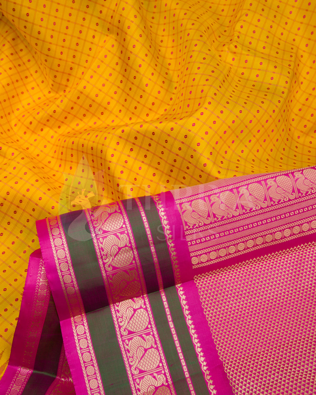 Close-up of yellow silk saree fabric with pink and gold zari woven border