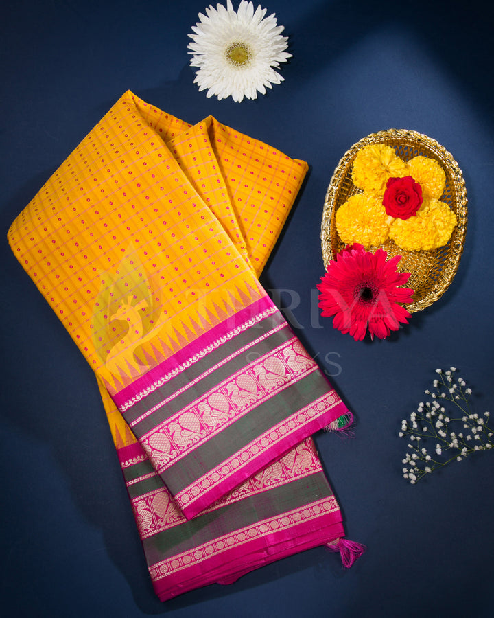 Styled flat-lay of yellow silk saree with pink border and floral decorations