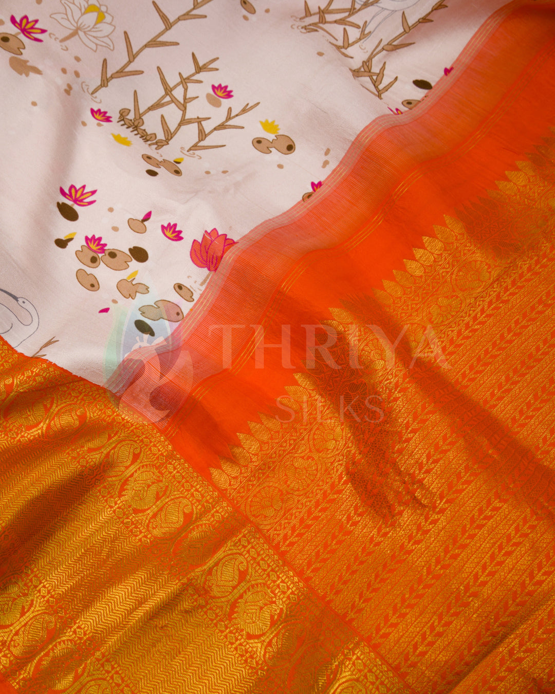 Close-up showing intricate golden orange zari work and delicate bird and lotus motifs on pastel pink silk